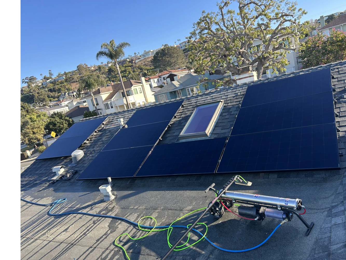 Solar panels installed on a rooftop with cleaning equipment nearby.