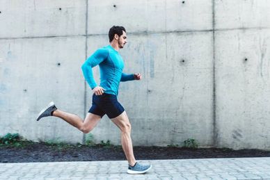 Man running outdoors beside a concrete wall.