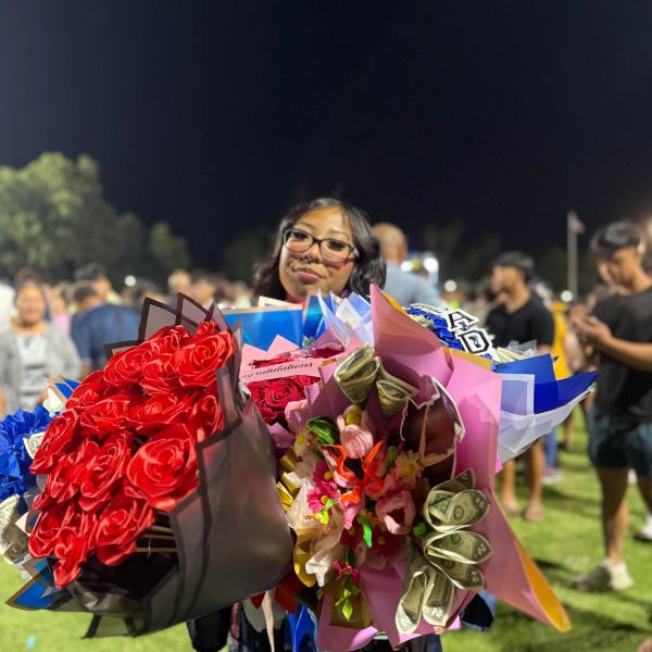 Young woman holding multiple colorful flower bouquets at night event.