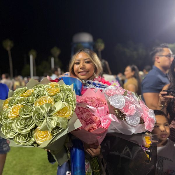 Young woman holding multiple flower bouquets at night celebration.