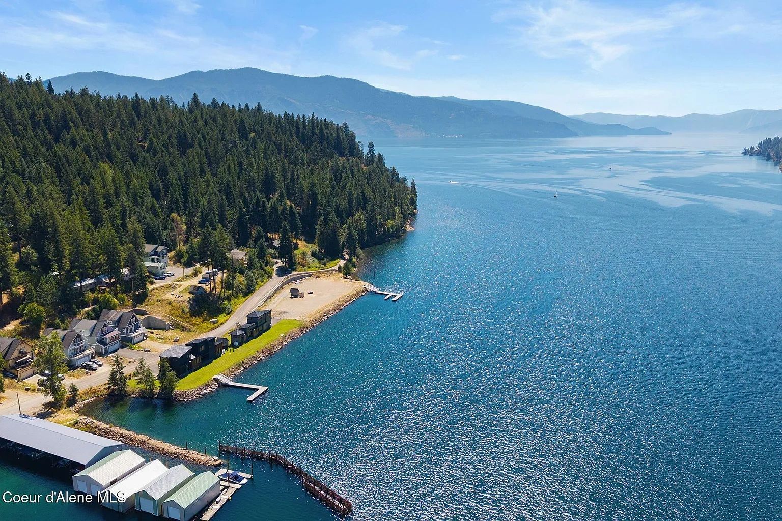 Scenic lakeside houses with docks and forest in the background.