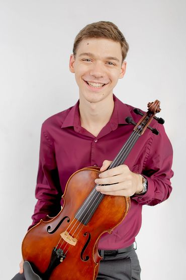 Young man smiling and holding a violin.