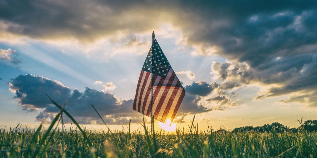 American flag waving in a field during sunset.