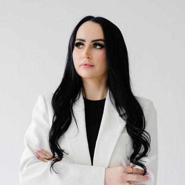 Confident woman with long black hair in a white blazer.