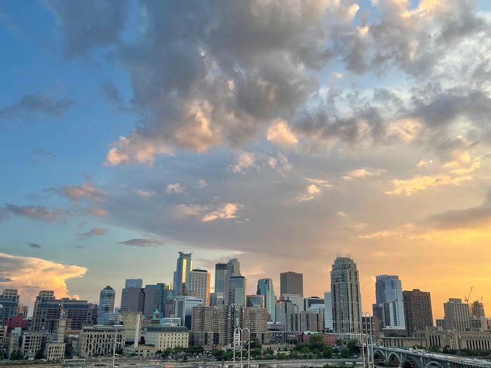 City skyline under a vibrant sunset with dramatic clouds.