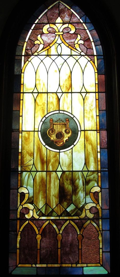Stained glass window with a central lyre symbol and intricate designs.