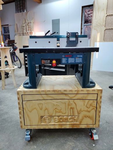 Bosch woodworking machine mounted on a wooden cart in a workshop.