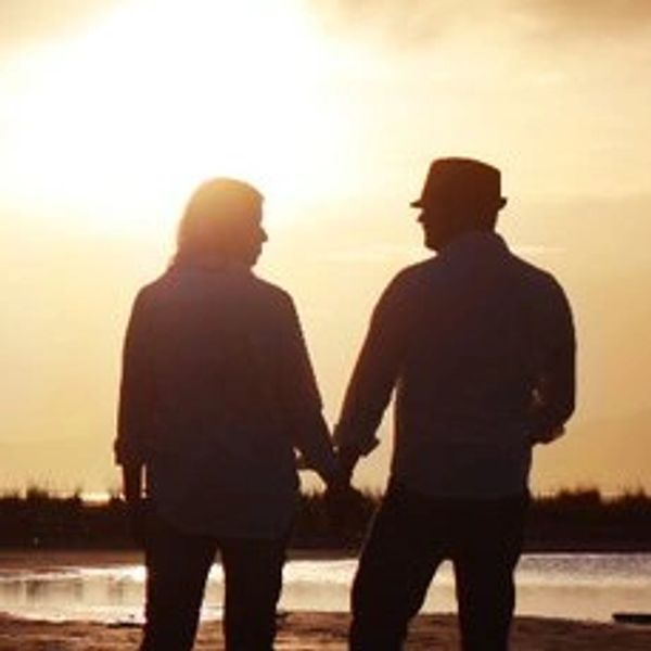 Couple holding hands at sunset by the water.