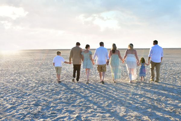 Family holding hands walking on the beach at sunset.