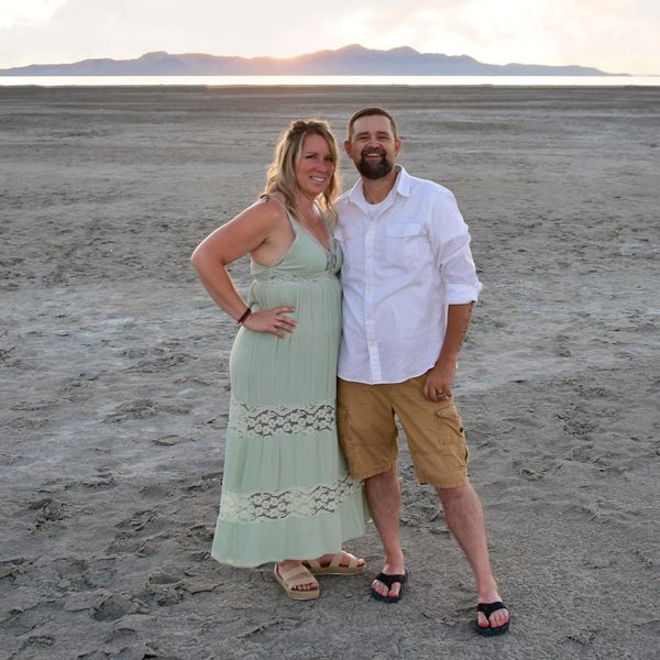 Couple standing on a dry beach at sunset.