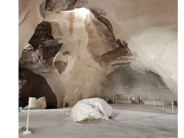 Natural cave interior with a large skylight illuminating the rocky formations inside.
