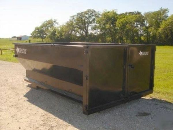 Large black metal dumpster container outdoors on gravel.