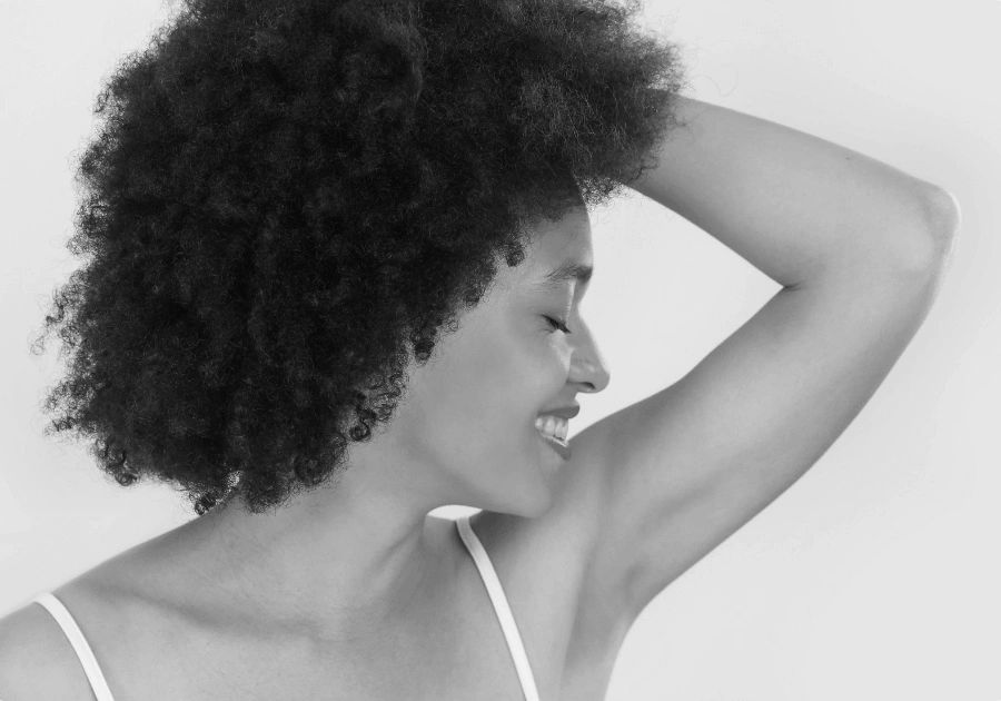 Black and white portrait of a woman smiling and showing smooth underarm skin.