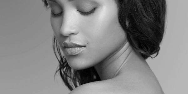 Black and white portrait of a woman with smooth, radiant skin and a calm, serene expression.