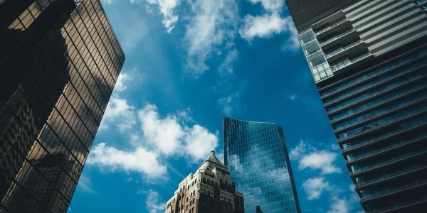 Blue sky with clouds above tall city buildings.