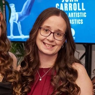 Woman with glasses and long curly hair smiling at an event.