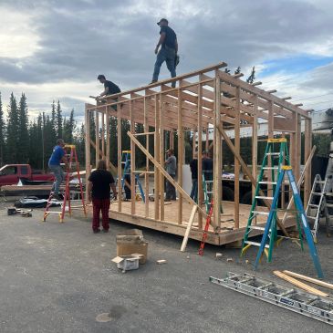 Group of people building a wooden structure outdoors.