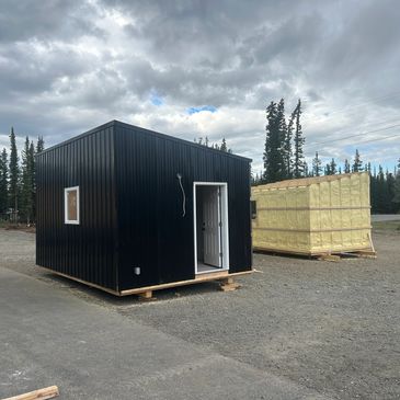 Small black structure and yellow insulation on pallets outdoors.