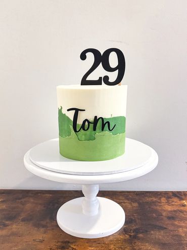 Ombré green cake with name charm and age topper in black.