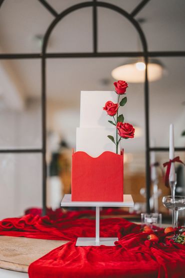 White and red square wedding cake with red rose sugar flowers.