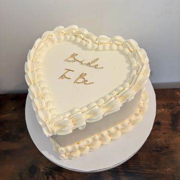 White vintage/lambeth style heart cake with bride to be cake charm in gold.
