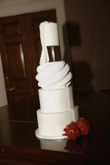 4 tier white wedding cake with textural swirls and pearl detail.