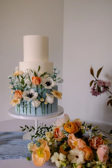 3 tier cake with dusky blue bottom tier and sugar flower meadow