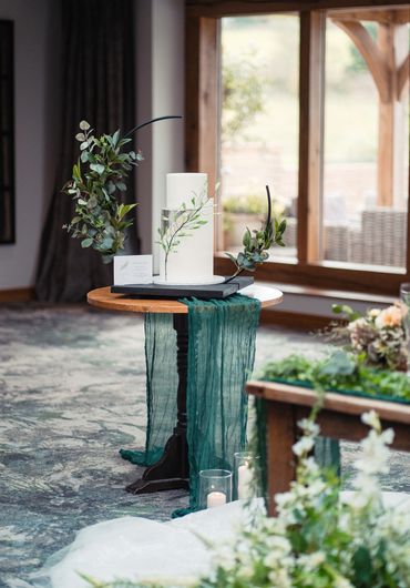Display of 3 tier white wedding with foliage detail, styled with green foliage and table runner