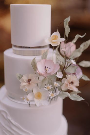 Close up of sugar flower details on white wedding cake.