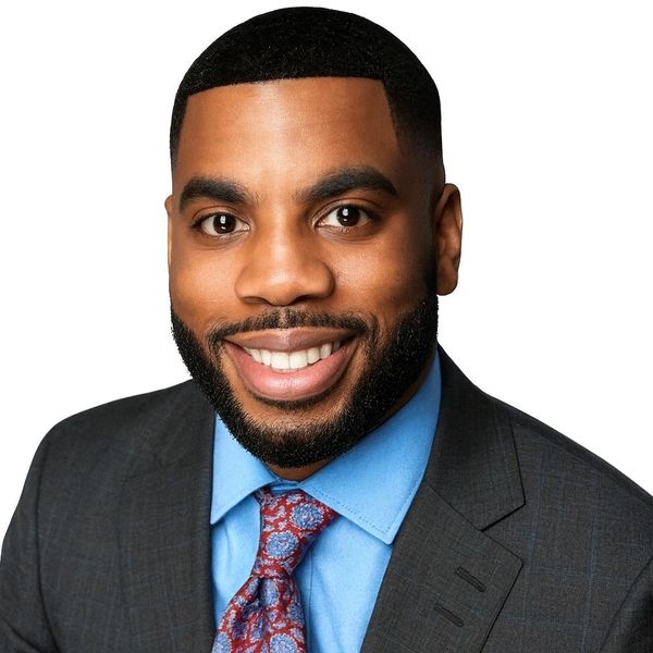 Smiling man in a suit and colorful tie against white background.
