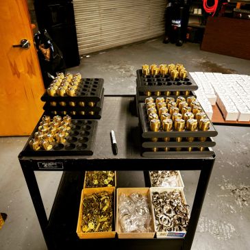Metal machine parts organized on trays and boxes in a workshop.