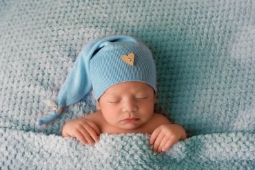 Sleeping newborn baby in a blue hat and blanket.