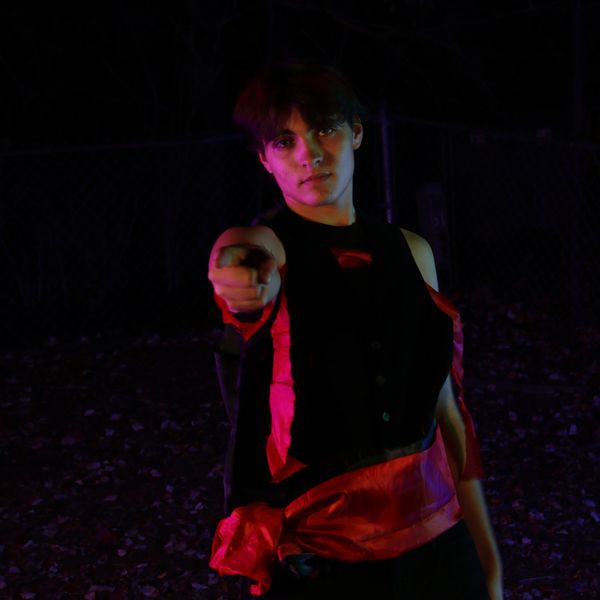 Person pointing towards the camera in dim lighting.