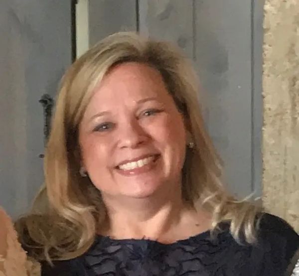 Smiling woman with blonde hair in a dark blue top.