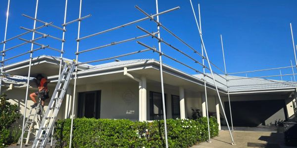 Scaffolding set up around a house under clear blue skies.