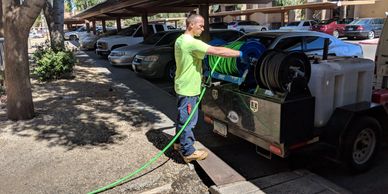 Worker using a hose reel machine to clean a parking area.