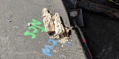 Broken grease pieces and a shovel on the ground with spray paint markings.