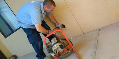 Worker using a machine to clear a pipe in a wall.
