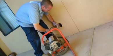 Worker using a machine to clear a pipe in a wall.