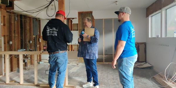 Three people inspecting a room under renovation.
