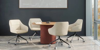 A modern office meeting room with beige swivel chairs and a round wooden table.