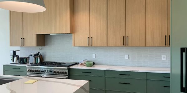 Modern kitchen with green lower cabinets and wooden upper cabinets.