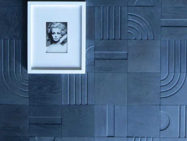 Framed black and white portrait on textured blue geometric wall.