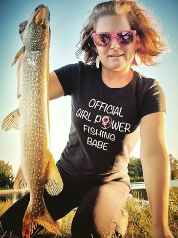 A woman wearing a Girl Power Fishing shirt while holding a fish