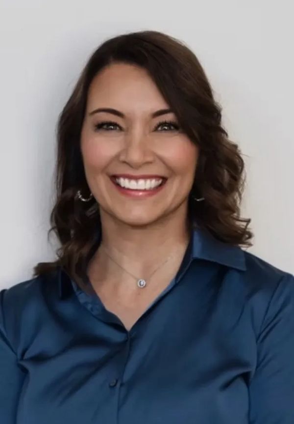 Smiling woman with wavy hair wearing a blue blouse.