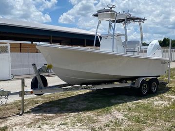 White motorboat on trailer under blue sky.
