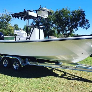 White center console boat on a trailer under a clear blue sky.