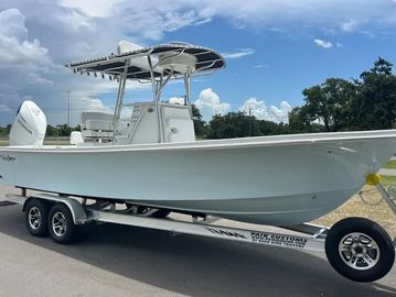 White motorboat on trailer under blue sky.