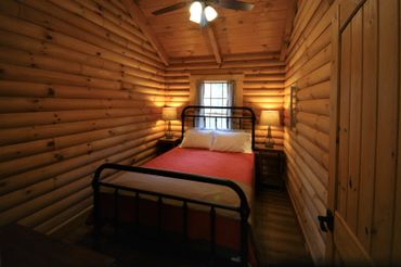 Queen bed with ceiling fan, light, two night stands, and lamps.