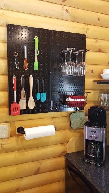 Close-up of kitchen utensils and wine glass wall display.
